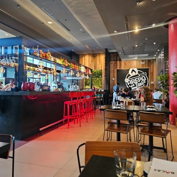 Bocas Grill interior with a long bar, red stools, and diners seated at tables.