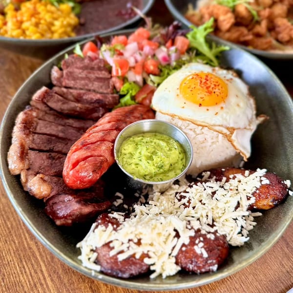 Bocas Grill's Latin-American dish with steak, sausage, rice, fried egg, salad, plantains, and green sauce.