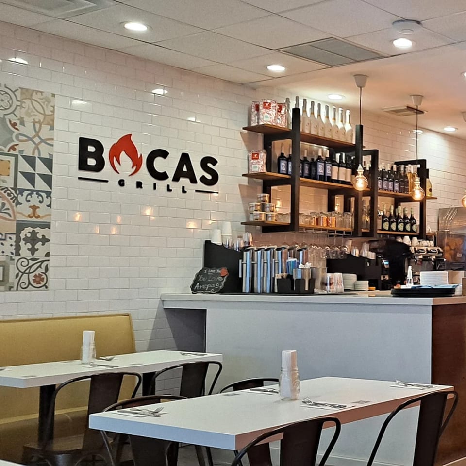 Interior of Bocas Grill restaurant with white subway tile, patterned accents, and a bar area.