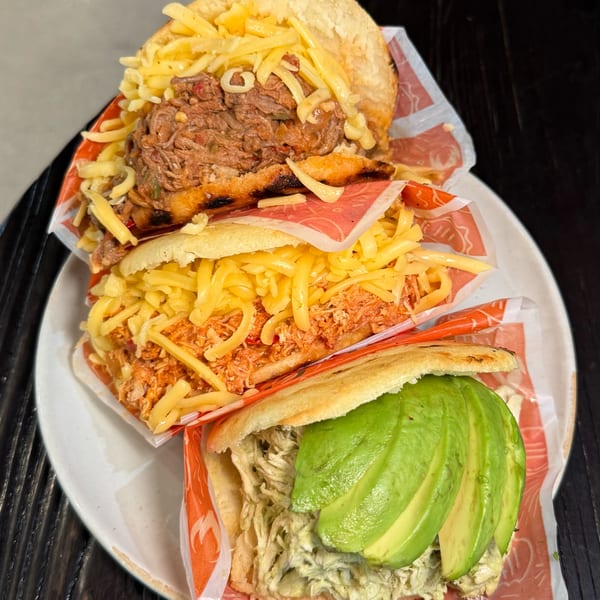 Three Bocas Grill arepas, one with shredded beef and cheese, one with chicken and cheese, and one with avocado.