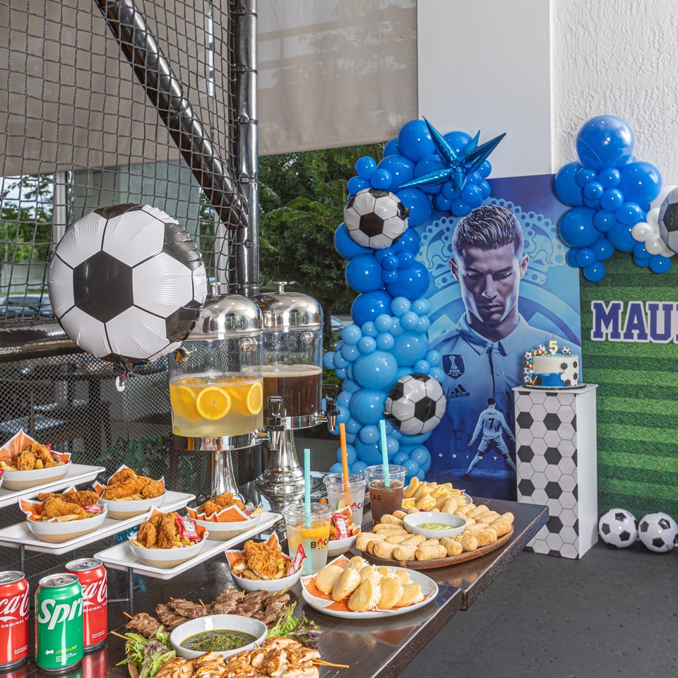 A soccer-themed party table with Latin-American food, drinks, and a Cristiano Ronaldo backdrop.